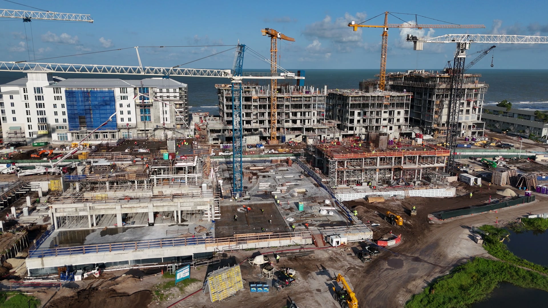 Drone view of a coastal construction site with tower cranes